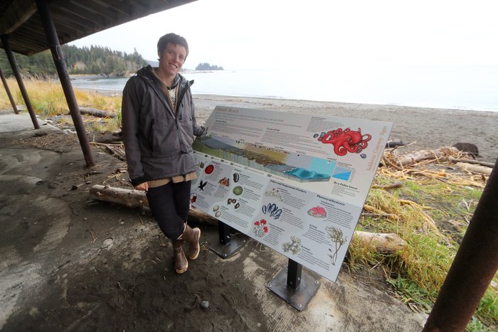Kim McNett stands beside an interpretive sign near Seldovia featuring her artwork.