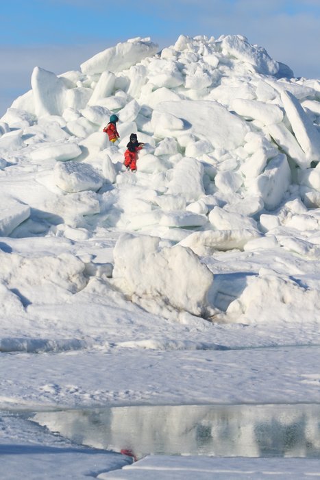 Kids climbing an ice jumble hill near a camp on the Chukchi Sea