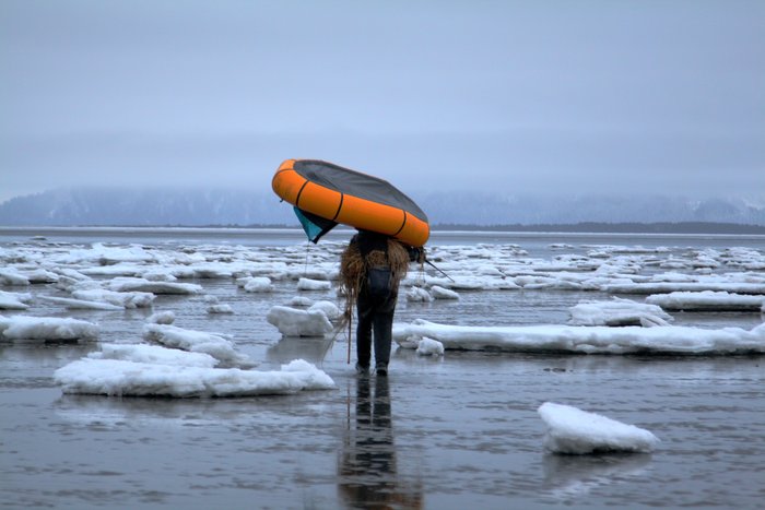Hig carries his packraft across the icy tide flats at Controller Bay.