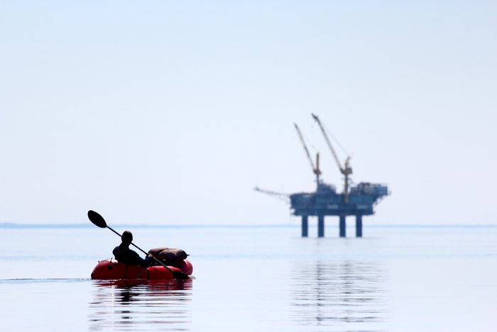 Paddling in calm seas, the oil rigs look closer and smaller than they really are.