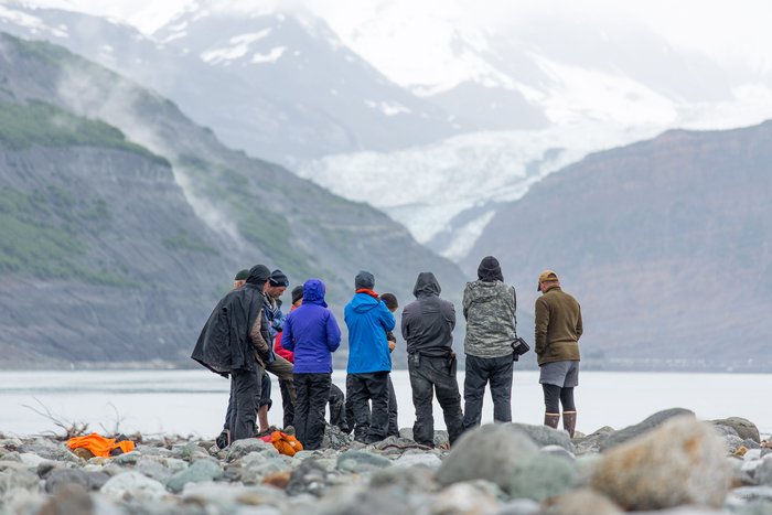 A group of scientists stand around a trench in Taan Fjord and discuss the landslide generated tsunami. During the summer of 2016, three expeditions to study this event were undertaken by experts from various earth-science fields. These expeditions allowed for greater collaboration and understanding between the fields of study. 