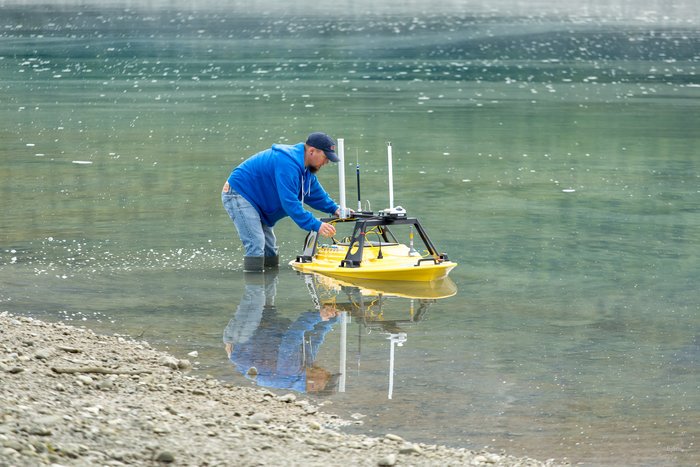 A geology student holds onto the several hundred thousand dollar, marine survey, remote control boat while the final preparations are conducted, before the first mapping survey.  