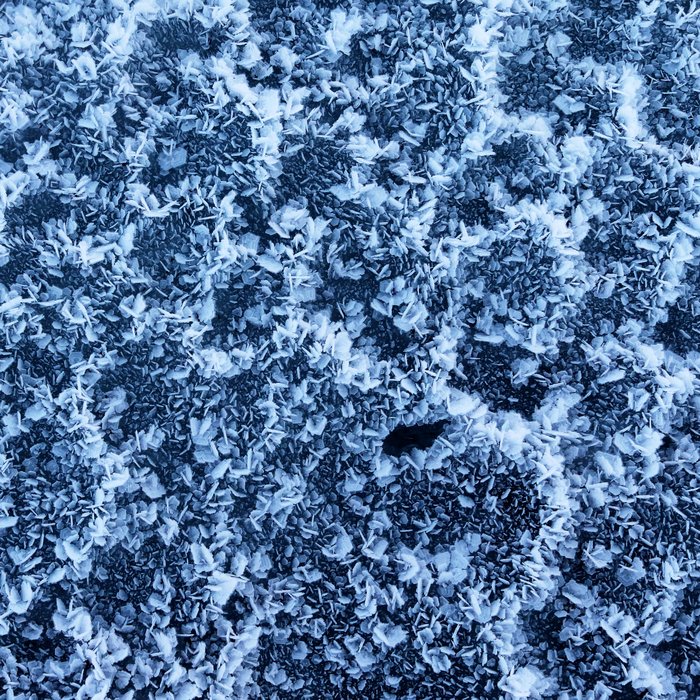 Frost crystals speckle the surface of an iceberg.