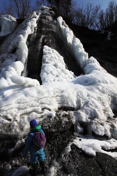 Sun works to melt out a partly frozen waterfall on a beach near Seldovia, Alaska.