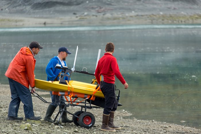 The marine survey crew launches the boat in the field for the first time. This unique, remote controlled boat is capable of mapping the sea floor in shallow water.  