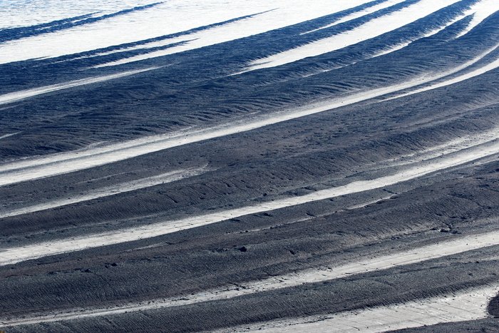 From far above the curving stripes of gravel-covered ice alternating with bright white dominate Malaspina Glacier.