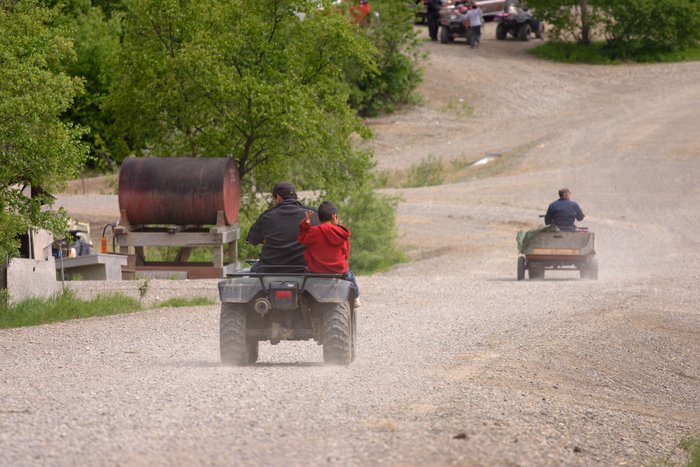 Boy waving from the back of a 4-wheeler in New Stuyahok. 