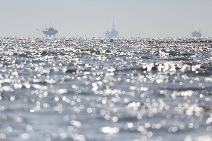 Blue in the distance, offshore oil rigs are visible from Trading Bay