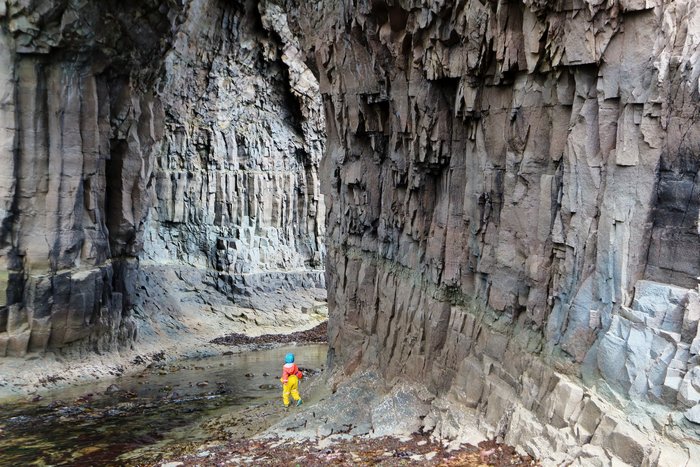 Exploring amongst cracked lava scoured into sea caves by giant waves in the Aleutians.