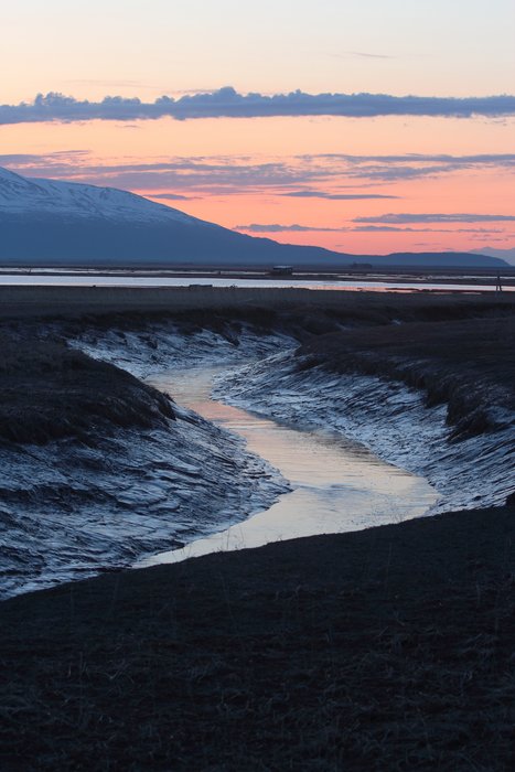 Sunset sky reflects in a muddy slough on the Susitna Delta